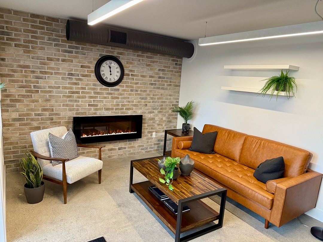 Restored lounge with leather sofa, exposed brick, and original concrete floors